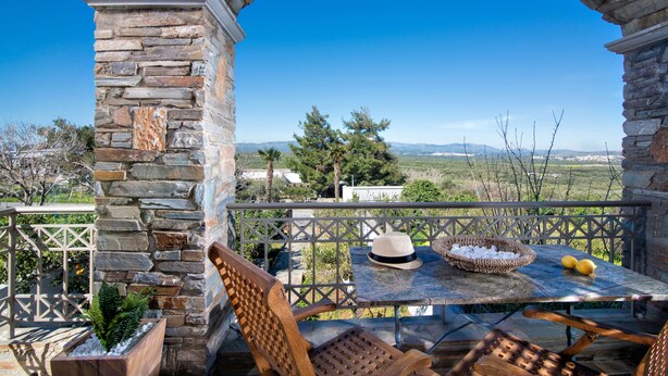 Un patio al aire libre con paredes de piedra, una mesa con sillas, un sombrero, limones y una cesta con hielo.