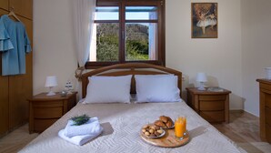 Una cama bien hecha con almohadas, una bandeja con croissants y jugo, y un cuadro en la pared.