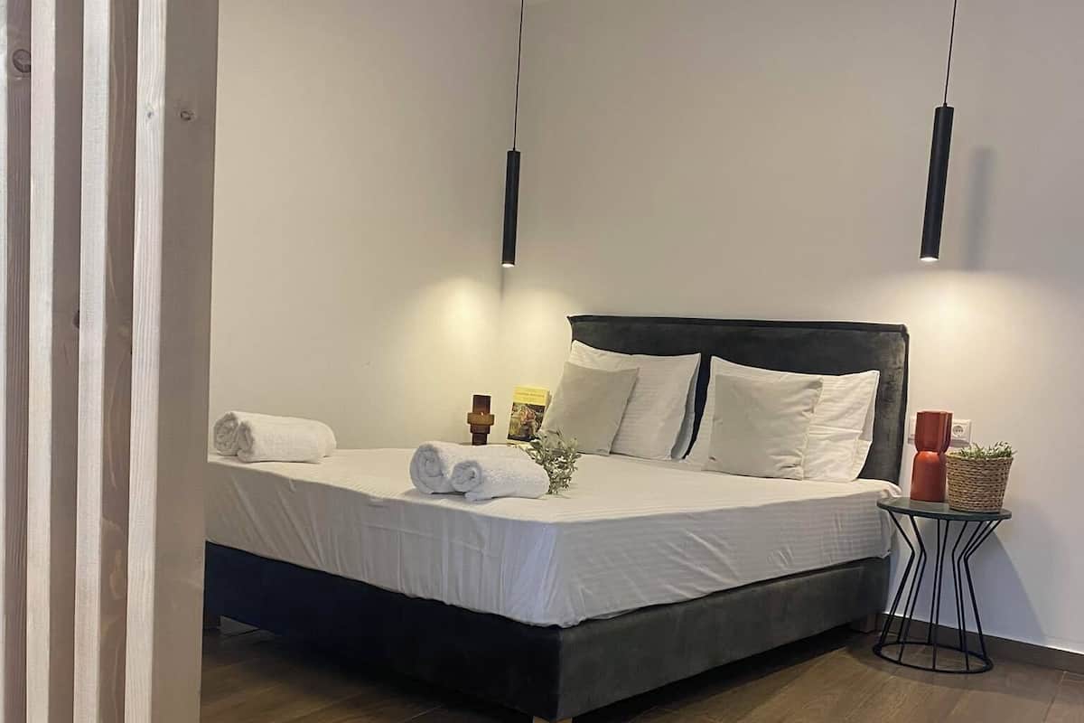 A modern bedroom with a bed, bedside tables, and a small side table with a plant.