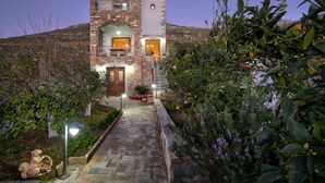 Un edificio de piedra con una entrada central, un balcón y un camino de jardín que conduce a la entrada.