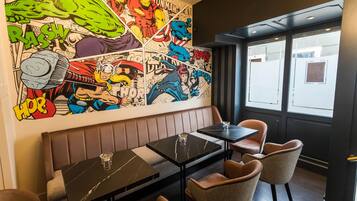 Interior de restaurante con un mural de estilo cómic, asientos de cuero y mesas de mármol negro.