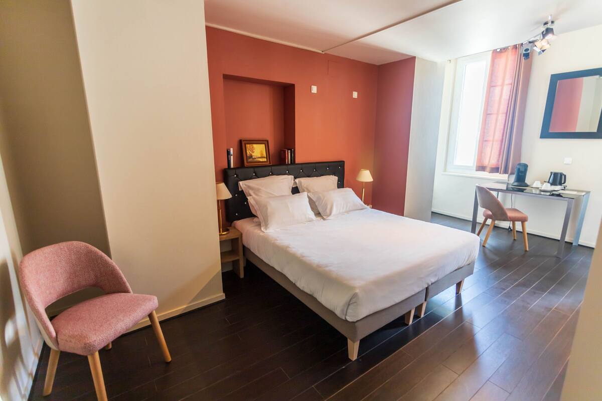Een slaapkamer met een bed, een bureau, een stoel en een nachtkastje.