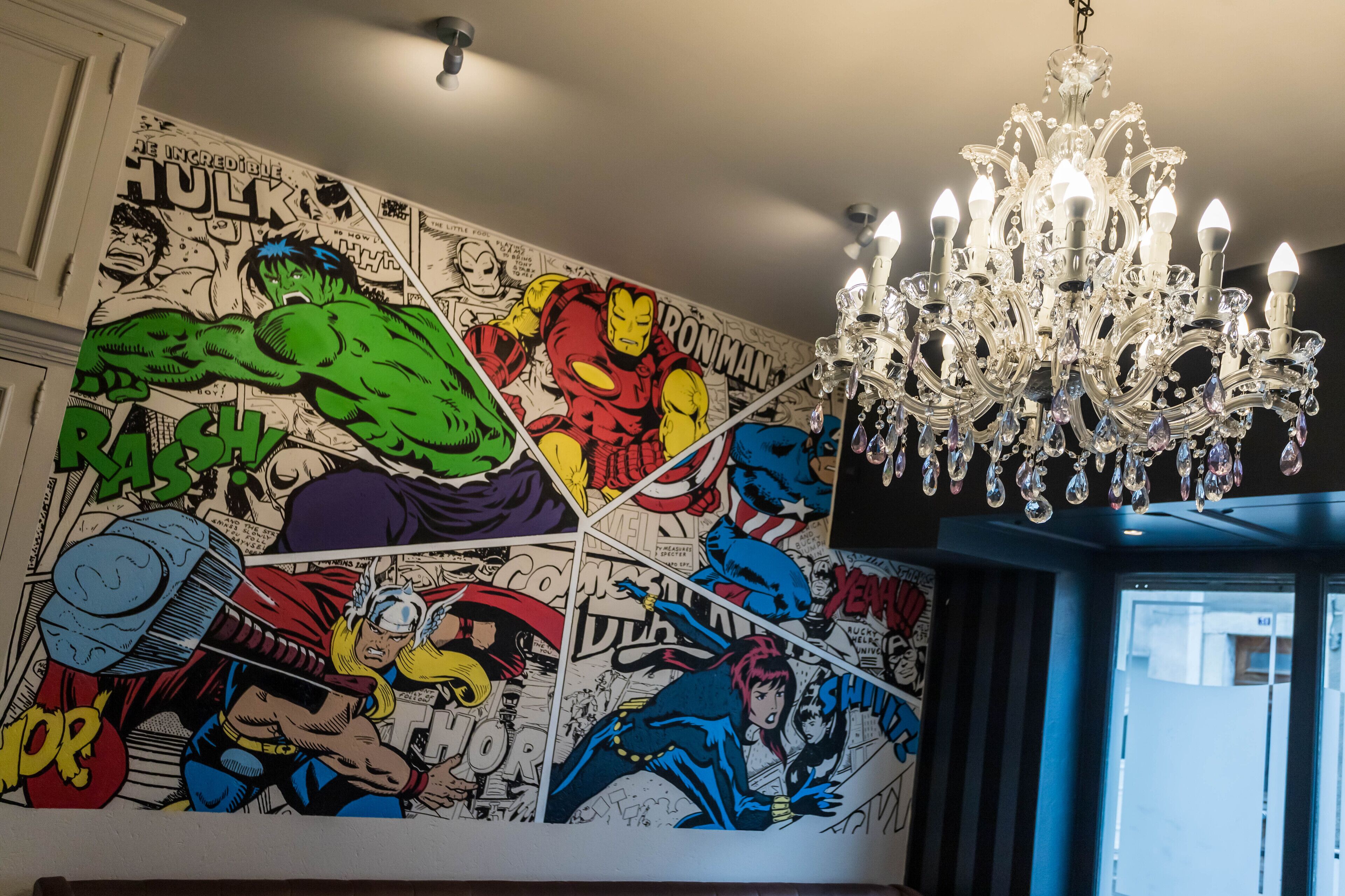 Ein Zimmer mit Wandgemälde im Comic-Stil und einem Kronleuchter.