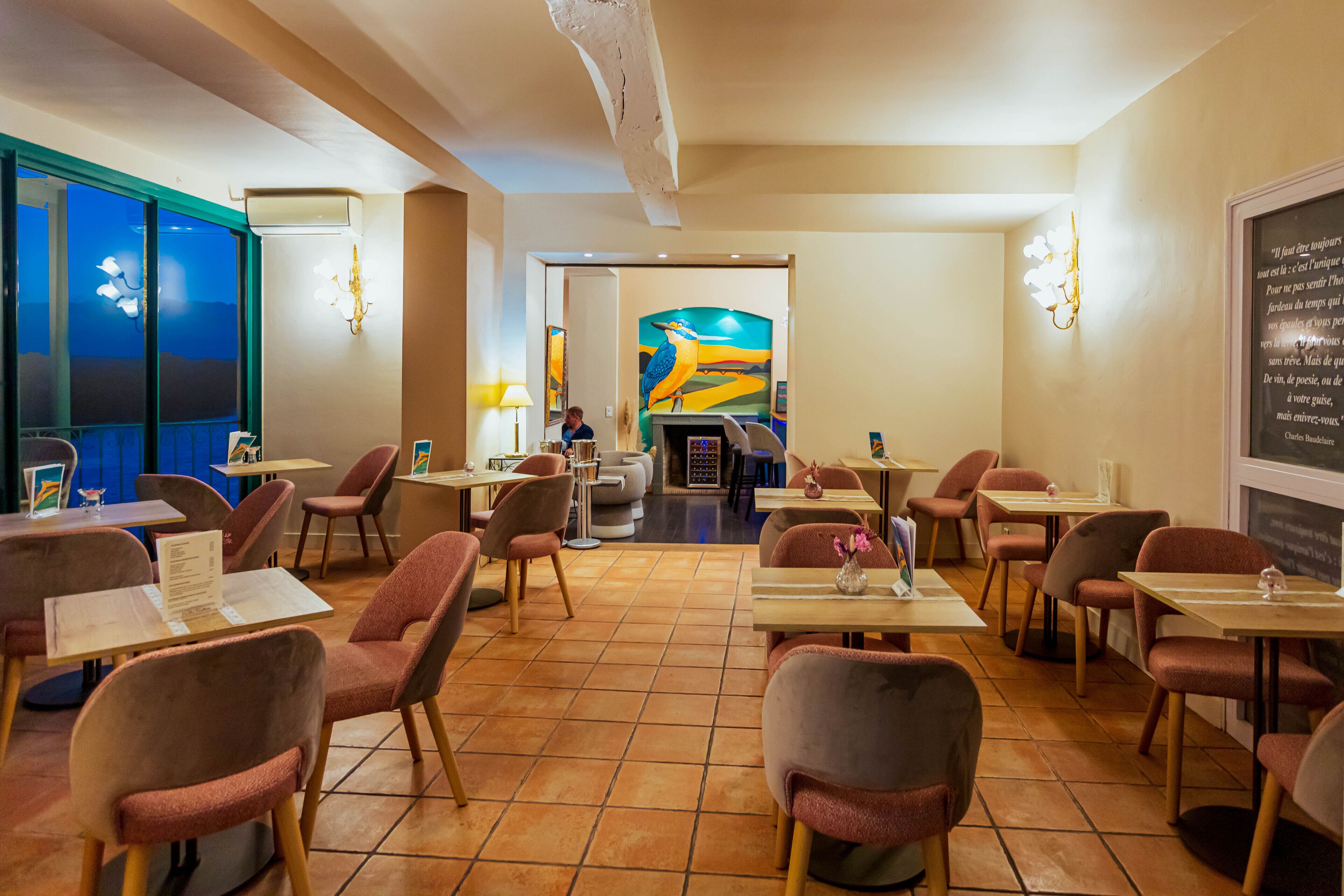 A restaurant with multiple tables and chairs, a large painting on the wall, and a view of the outside.