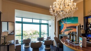 A modern bar area with a view of the outdoors, a chandelier, and seating. - Côté Garonne-Le balcon des dames (Tonneins)