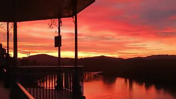 A sunset view from a balcony overlooking a body of water with distant hills.