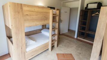 A bunk bed with a wooden frame and a wardrobe with open doors.