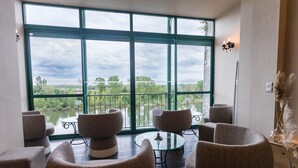 A balcony with wicker furniture and a glass table, overlooking a lake and greenery. - Côté Garonne-Le balcon des dames (Tonneins)