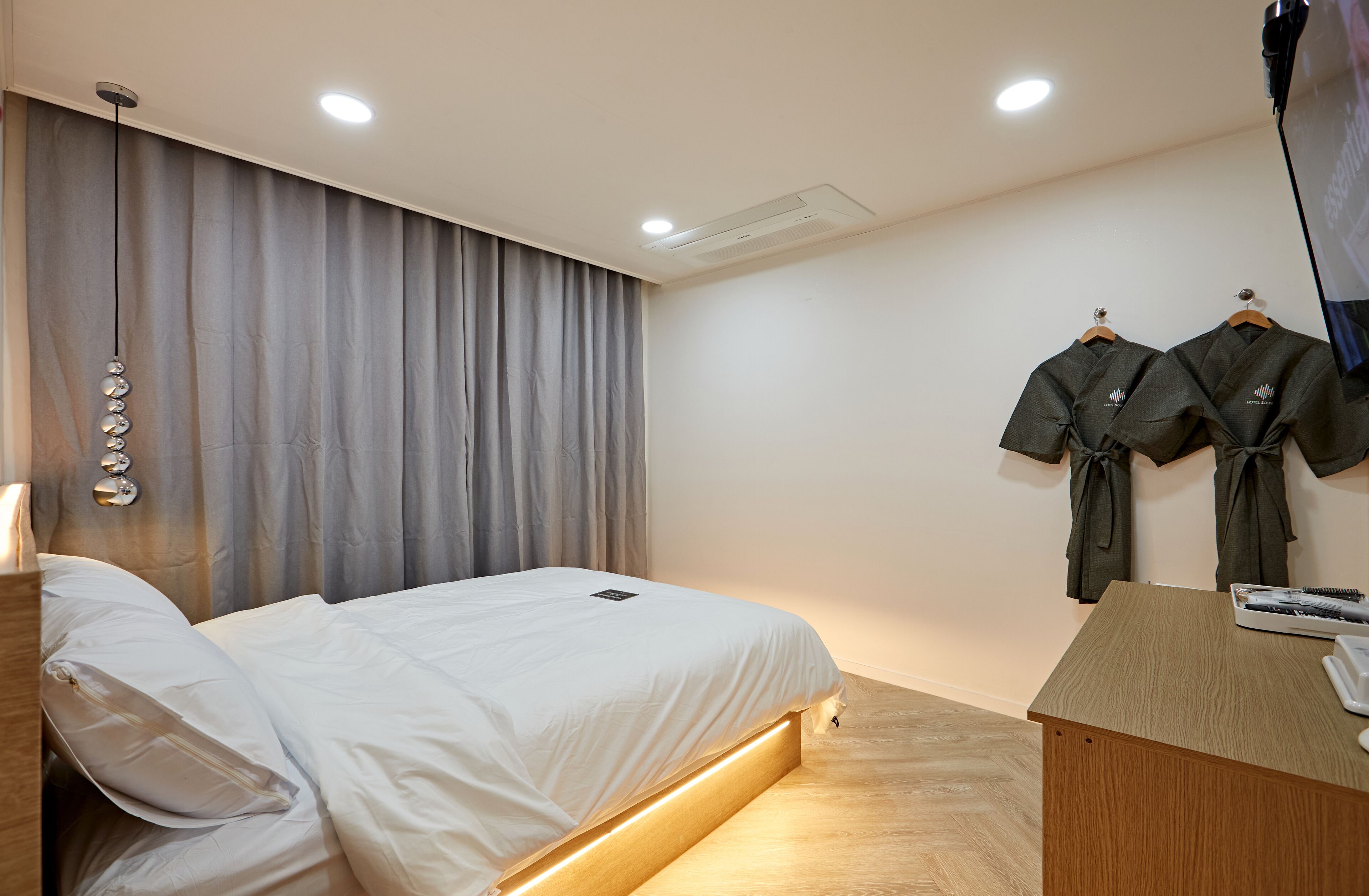 A modern hotel room with a bed, bedside table, and a desk with a phone.