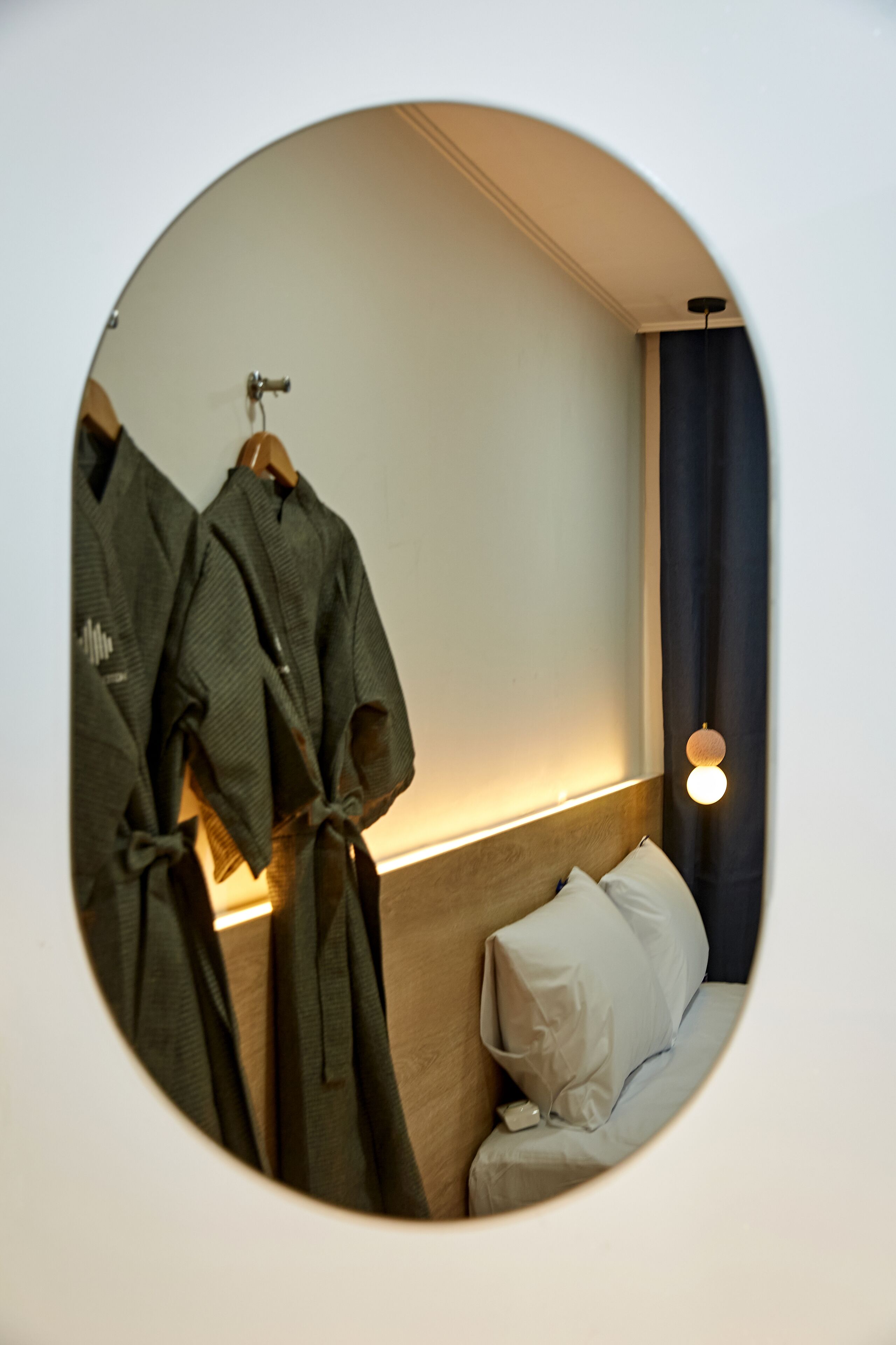 Vista circular de una habitación de hotel con una cama, una mesita de noche y dos batas colgadas en un perchero.