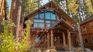 A log cabin with a large glass window, wooden exterior, and a stone foundation.