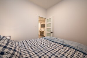 Une chambre à coucher comprenant un lit, une table de chevet et une porte donnant sur une salle de bain.