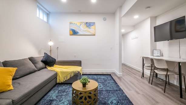 Una sala de estar moderna con un sofá, una mesa de centro redonda y un televisor montado en la pared.