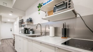 Una cocina moderna con gabinetes blancos, una campana de acero inoxidable y un horno empotrado.