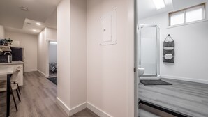 Una habitación moderna y luminosa con piso de madera, un escritorio con silla, una cama con cabecera negra y una ventana con vistas.