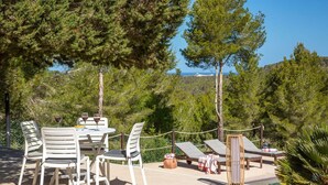 An outdoor seating area with a table and chairs, lounge chairs, and a pool. - SES SAVINES A charming, peaceful house with a pool and BBQ, 2km from the beach (Illes Balears)