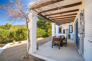Un espacio al aire libre techado con mesa y sillas, una pérgola y vistas del paisaje circundante.
