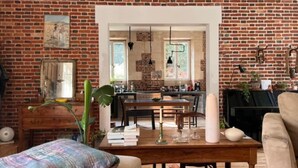 A cozy living room with a brick wall, a dining area, and a kitchen visible through an open doorway.