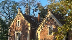 A two-story brick building with a gabled roof and dormer windows.