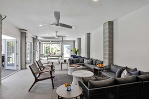 A modern living room with a sofa, chairs, a coffee table, and a ceiling fan.