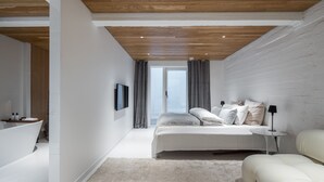 A modern bedroom with a large bed, a bedside table, a sofa, and a view of the outdoors through a window. - Nordic townhouse with own sauna at the city center of Helsinki (Helsinki)