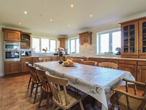 A kitchen with wooden cabinets, a dining table with chairs, and a fruit bowl.