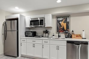 Una cucina moderna con elettrodomestici in acciaio inossidabile, mobili bianchi e una macchina per il caffè.