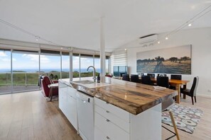 Enjoy meals in the adjacent dining area with a large table and chairs, overlooking the surrounding landscape from the spacious balcony.