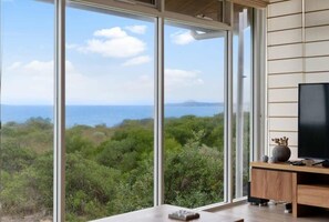 Enjoy a panoramic view of the lush landscape and ocean from this room's large sliding glass door.