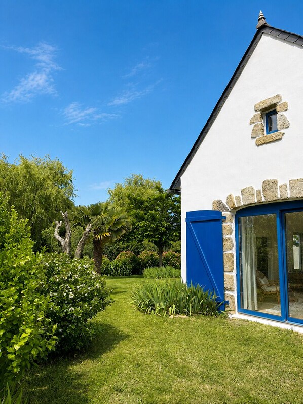 Un bâtiment blanc agrémenté de détails en pierre, une porte bleue et une fenêtre encadrée de pierre.