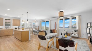 A spacious living area with a large window, a sofa, a coffee table, and a dining area.