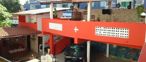 Un edificio de varios pisos con fachada roja y azul, un estacionamiento techado y un mural en la pared inferior.