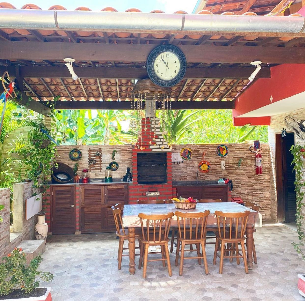 An outdoor kitchen area with a brick oven, wooden chairs, and a table.