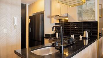 Eine moderne Küche mit einem Edelstahl-Kühlschrank, einer schwarzen Arbeitsplatte und einem integrierten Weinkühlschrank.