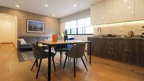 Una cocina moderna con armarios de madera, un comedor con mesa y sillas, y vistas al exterior a través de amplios ventanales.