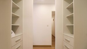 Un pasillo estrecho con paredes blancas y suelo de madera que conduce a una puerta al final.