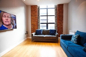 Relax in this stylish living room with a city view, featuring a sofa, armchair, and flat-screen TV.