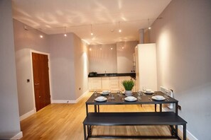 Enjoy meals in this cozy dining area with a table for four, kitchen in the background, and a potted plant adding a touch of greenery.
