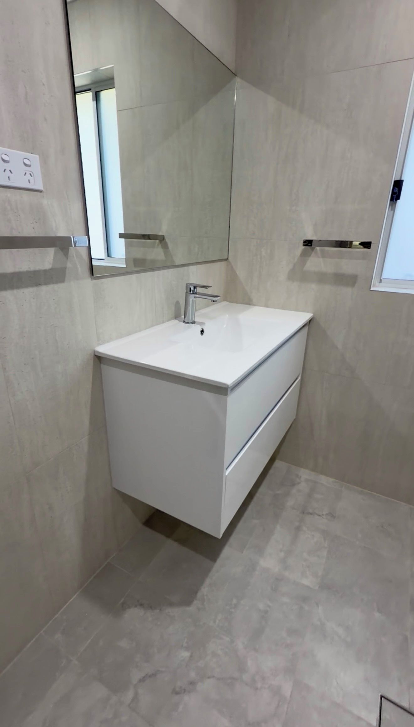 Un bany modern amb un lavabo blanc, un mirall i una zona de dutxa.