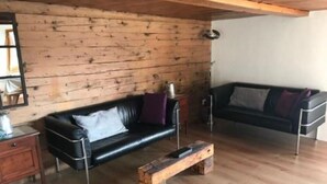 Un soggiorno moderno con pareti in legno, due divani in pelle nera, un tavolino in legno e un comodino in legno.