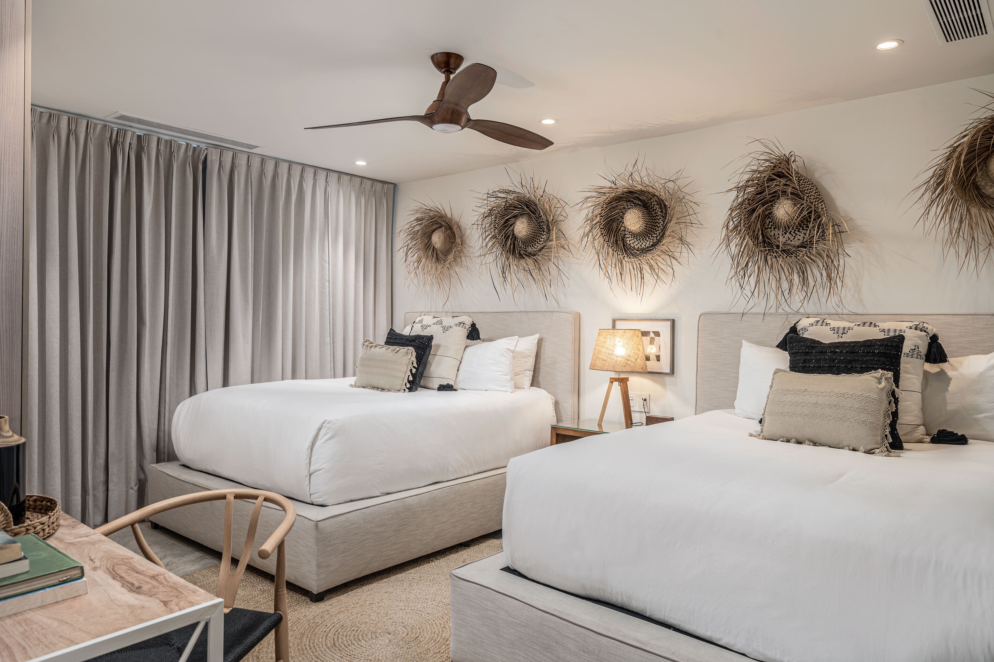 A hotel room with two beds, a ceiling fan, and decorative wall art.