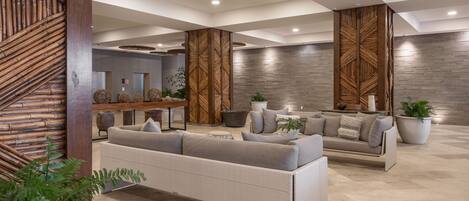 Eine moderne Lobby mit einem Ecksofa, einer Holz-Akzentwand und einem Empfangstresen.