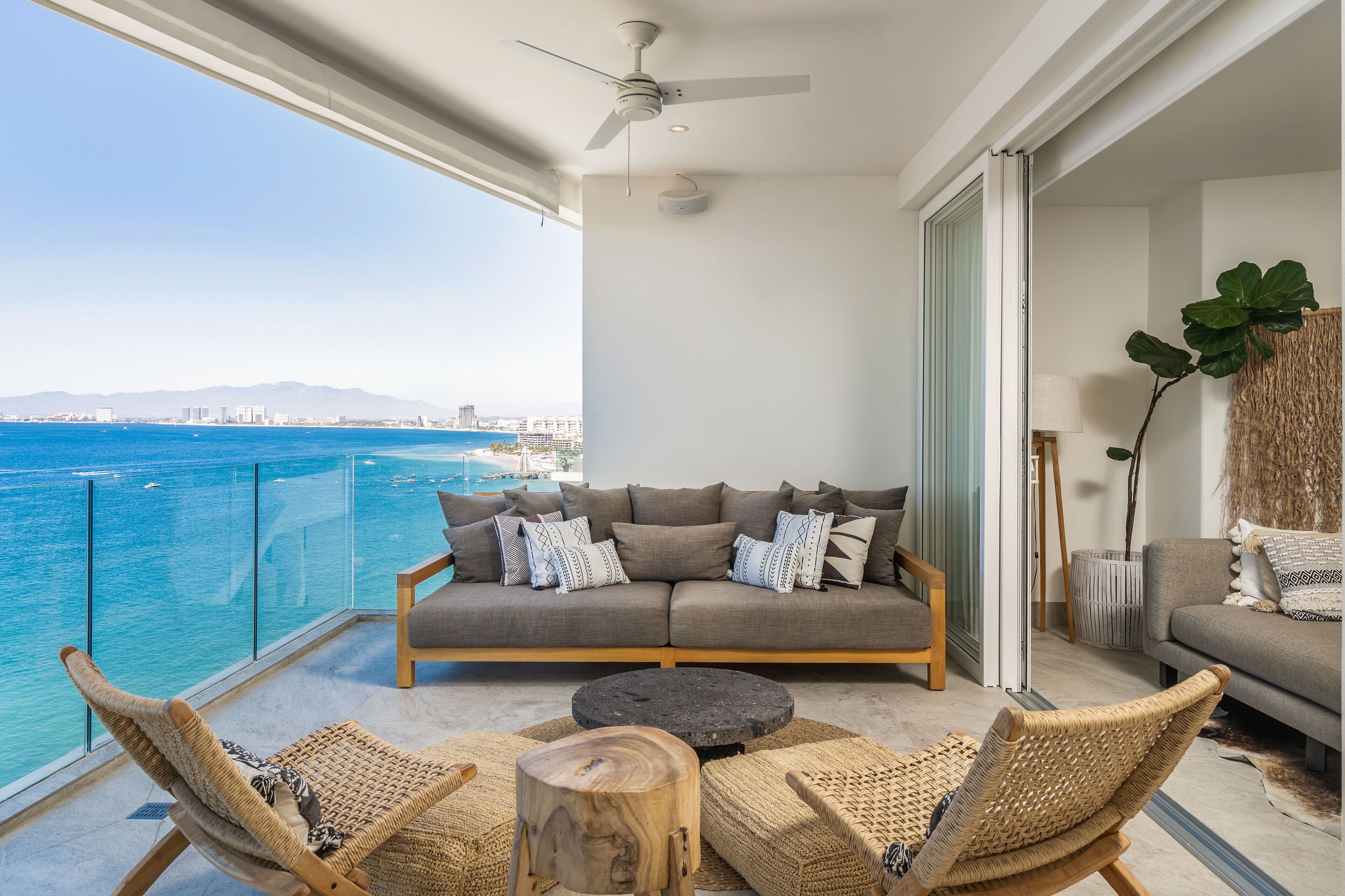 A balcony with a sofa, wicker chairs, and a round table.