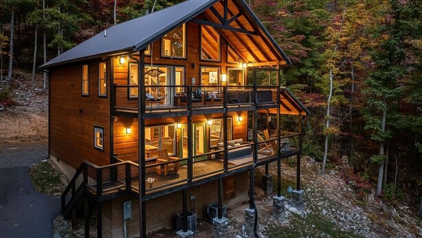 Une cabane en rondins à plusieurs étages, dotée d’un balcon et entourée d’un feuillage automnal.