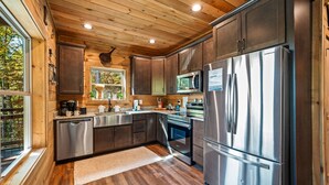 Une cuisine moderne dotée d’appareils électroménagers en acier inoxydable, de meubles en bois et d’une grande fenêtre.
