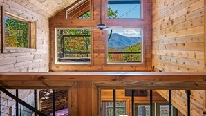 Une cabane en bois dotée de nombreuses fenêtres donnant sur les montagnes.