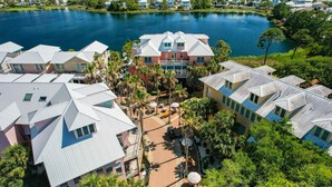 An aerial view of a residential area with houses, a central building with a red facade, and a lake. - Stella By The Sea 3 Bedroom Home by RedAwning (Panama City Beach)