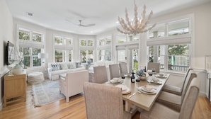 A spacious dining area with a long table set for six, surrounded by comfortable seating. - Stella By The Sea 3 Bedroom Home by RedAwning (Panama City Beach)