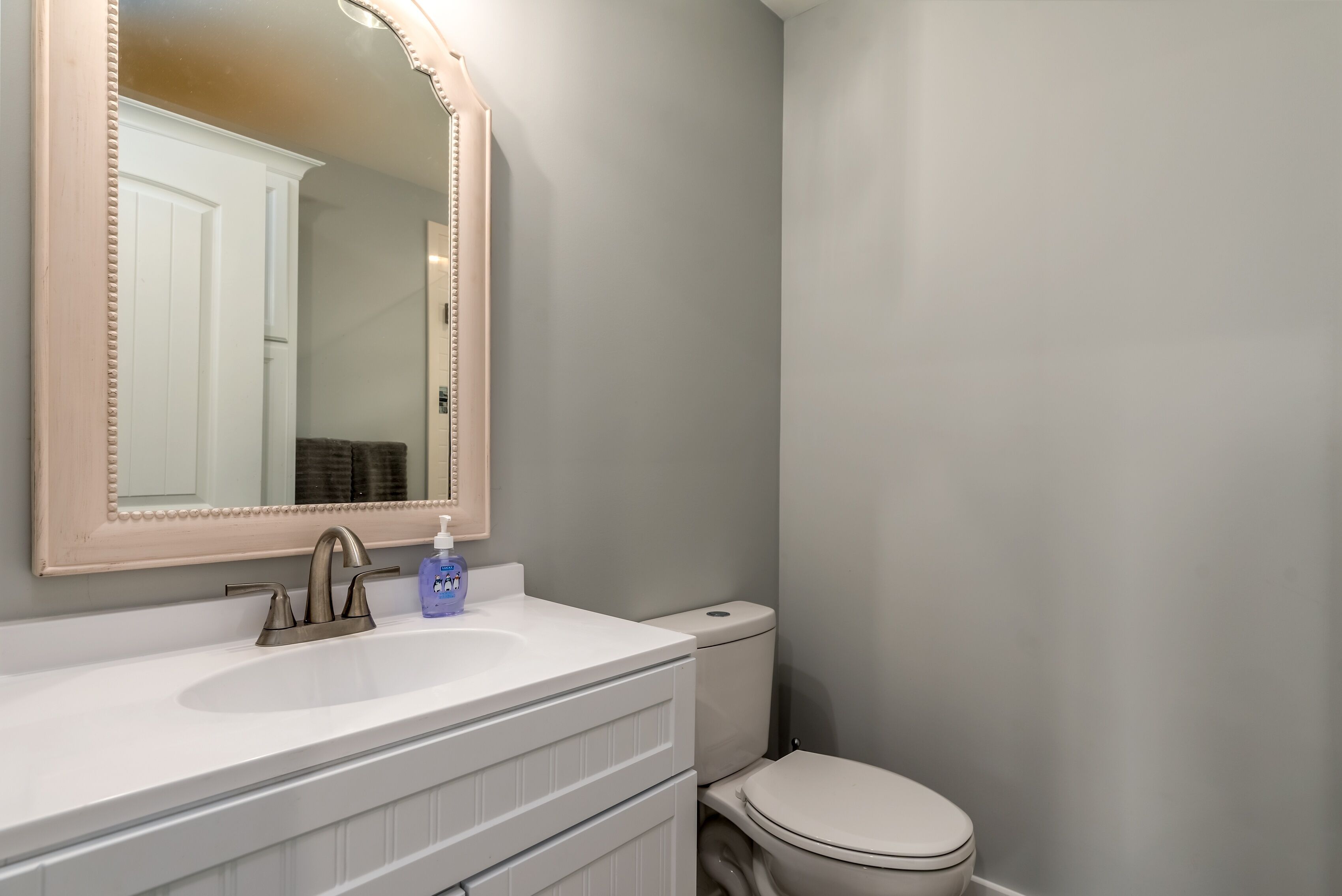 A bathroom with a white sink, a mirror with a lighted frame, and a toilet.