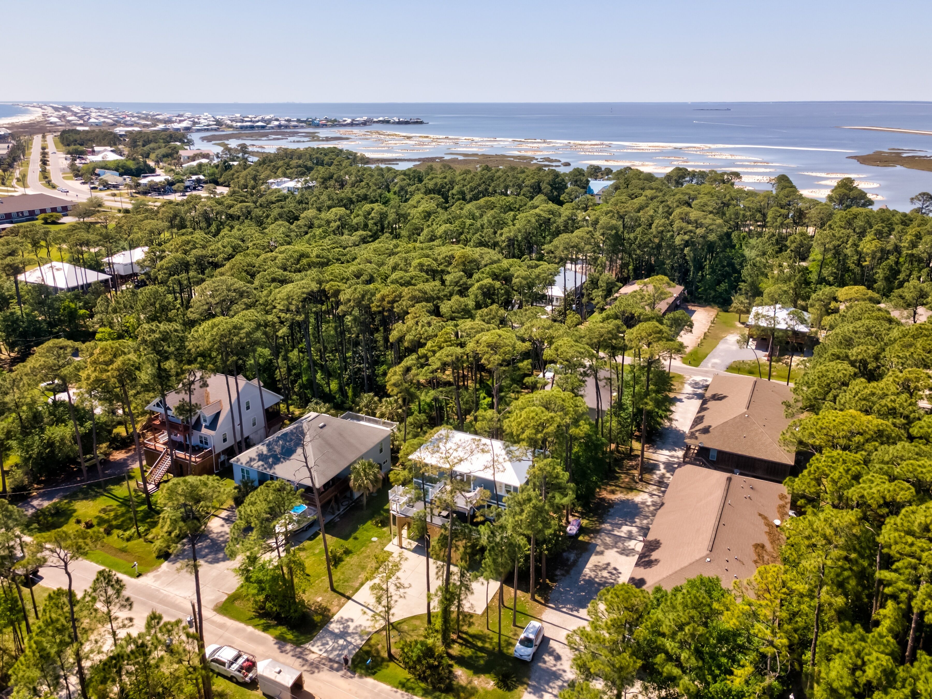 An aerial view of a residential area with houses, roads, and a beach in the background.